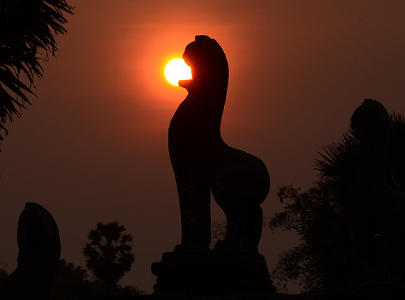 Swallowing The Sun lion statue in Angkor Wat during sunset photo Alexander Krivenyshev WorldTimeZone
