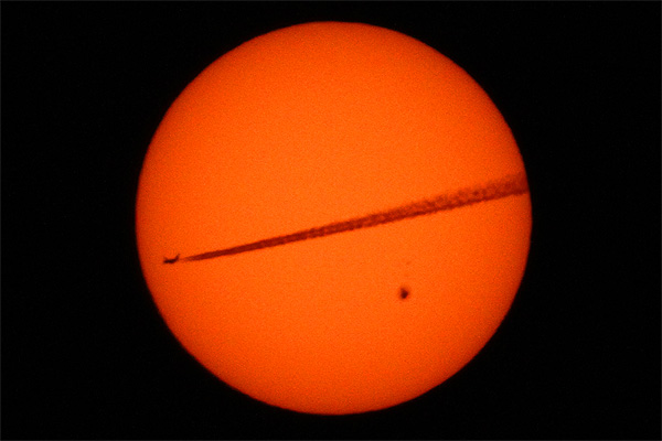 Airplane crossing the sun's face with giant heart-shaped sunspot active region 2529, photo taken from Hoboken Hoboken New Jersey photo Alexander Krivenyshev WorldTimeZone