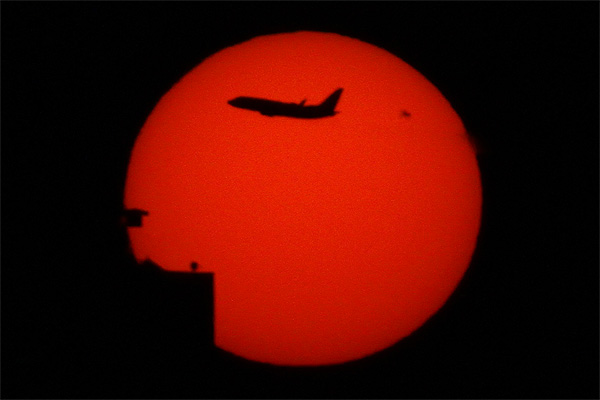 Airplane from JFK airport passing in front of the Sun with sunspot AR2529 over Manhattan New York photo Alexander Krivenyshev WorldTimeZone