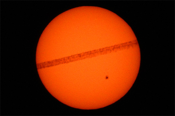 Airplane jet contrail in front of the sun with sunspot AR2529 photo taken from Weehawken New Jersey photo Alexander Krivenyshev WorldTimeZone